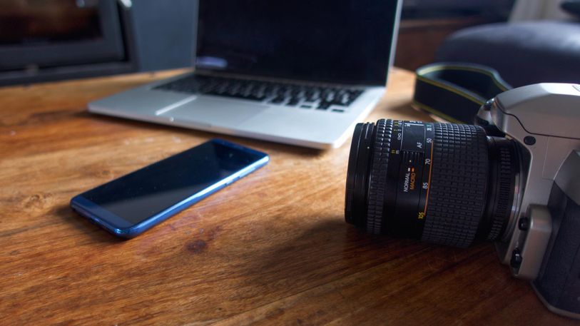 an-old-35mm-slr-camera-on-a-coffee-table-alongside-a-modern-smar